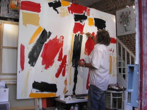 Philippe Cloart peignant une grande toile abstraite rouge, noire et jaune dans son atelier
